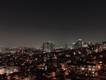 Illuminated buildings in city against sky at night