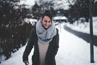 Smiling young woman walking on snow covered land