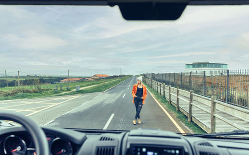 View from inside camper van of woman posing on the road