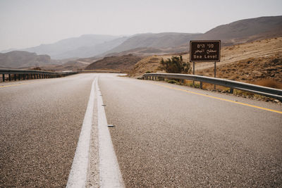 Road leading towards mountains against sky