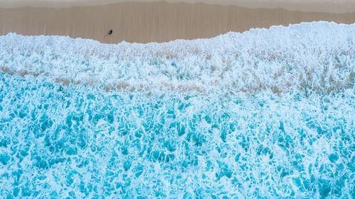 Aerial top view of sandy beach with travelling tourists in beautiful the sea wave abstract 