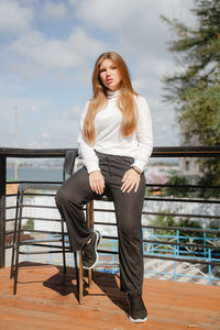 Portrait of young woman sitting on pier