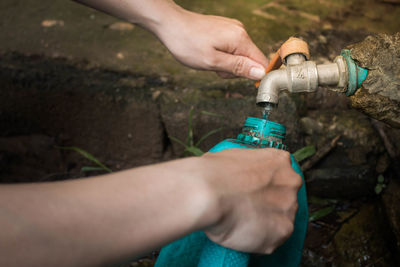 Close-up of man filling water in can