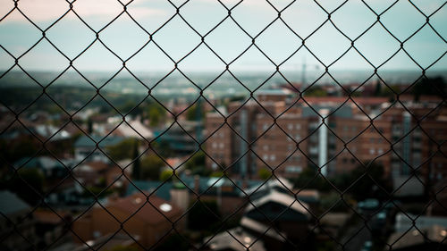 Full frame shot of chainlink fence against cityscape
