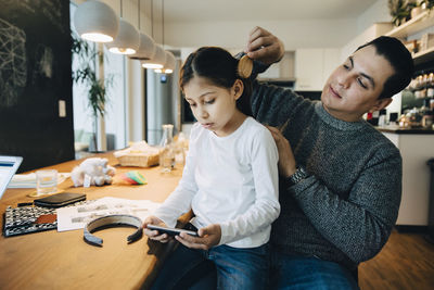 Young woman using mobile phone while sitting on table