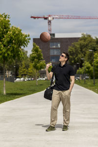 Close-up of mature man throwing basketball while standing outdoors