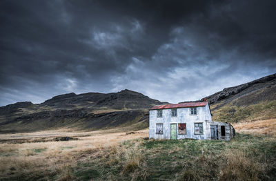 House on field against storm clouds