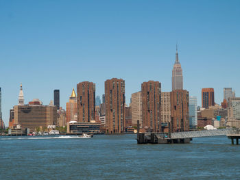 Sea by cityscape against clear sky