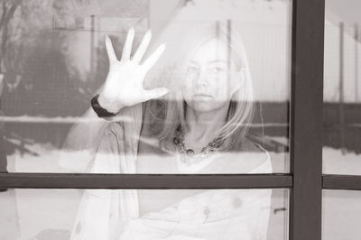 Portrait of woman standing by glass window