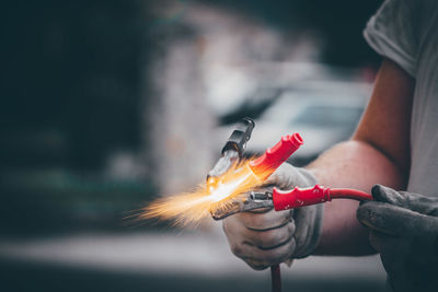 Midsection of man holding fire against blurred background