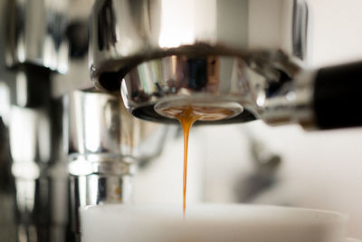 Cropped image of coffee maker pouring in cup at cafe