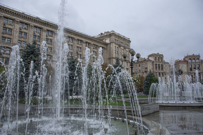 Fountain in city against sky