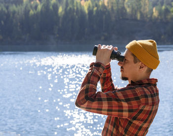 Side view of woman photographing sea against sky