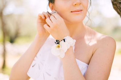 Midsection of woman holding white flower