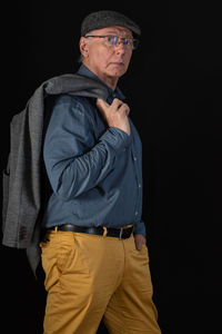 Portrait of man with jacket standing against black background