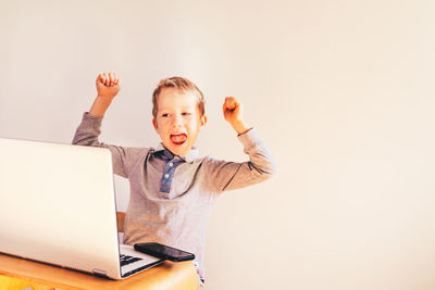 Full length of boy using mobile phone against white background