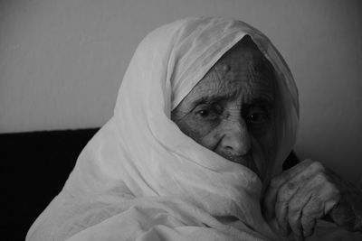 Close-up portrait of senior woman in sari relaxing while sitting on sofa at home