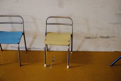 Empty chairs and table against wall