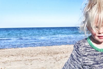 Cropped image of cute girl at beach against clear sky