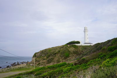 Lighthouse by sea against sky