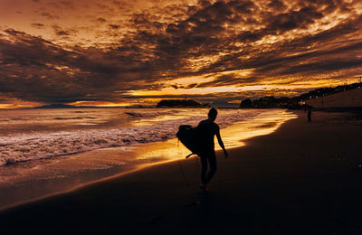 Silhouette man on beach against sky during sunset