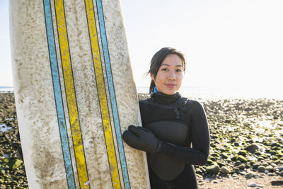Smiling asian woman with a healthy lifestyle going winter surfing