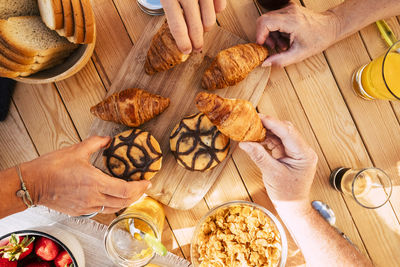 Cropped hands of people having sweet food over table in cafe