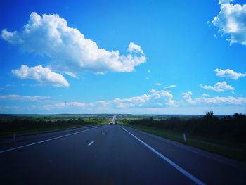 Road by landscape against blue sky