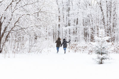 Rear view of woman walking on snow covered land