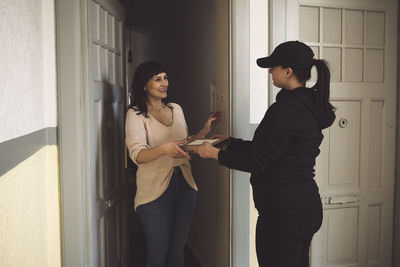 Delivery woman delivering package to smiling customer at doorstep