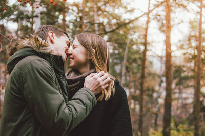 Couple kissing against trees