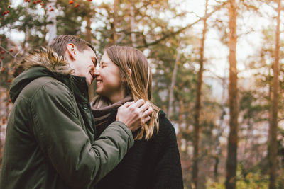 Smiling couple embracing against trees