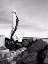 Driftwood on rocks by sea against sky