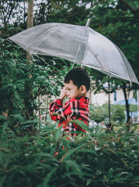 Boy holding umbrella in rain during rainy season