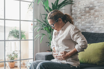 Side view of woman using laptop while sitting on sofa at home