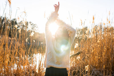 Rear view of woman with arms raised standing in forest