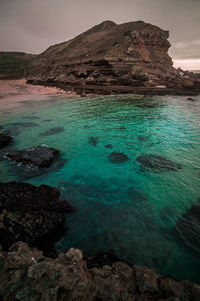 Scenic view of rocks in sea against sky
