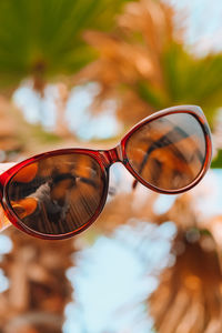 Close-up of sunglasses on glass against sky