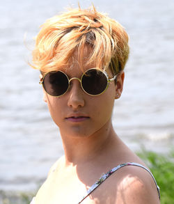 Portrait of woman with short hair wearing sunglasses against lake