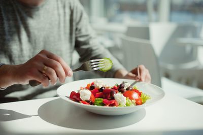 Midsection of person eating salad in restaurant