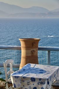 Empty chairs by sea against sky