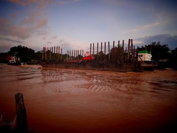 Scenic view of river by buildings against sky at sunset