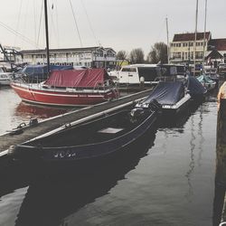 Boats moored at harbor against sky