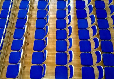 High angle view of empty blue chairs arranged in order at convention center