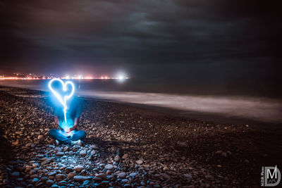 Light trails on beach against sky at night