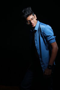 Young man standing against black background