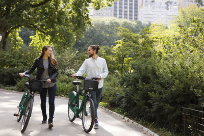 Couple talking while walking on footpath with bicycles