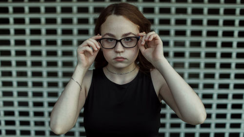 Portrait of young woman standing against wall