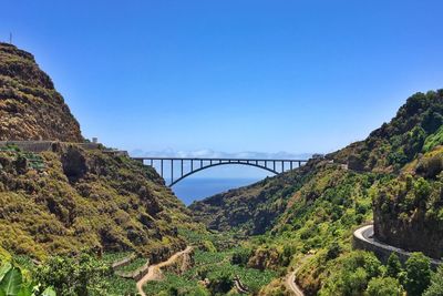 Arch bridge over bay against clear blue sky