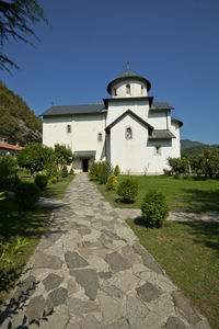 Footpath amidst buildings against clear blue sky